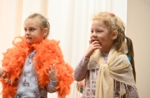 Dwie dziewczynki na scenie. Jedna ma boa z piór 