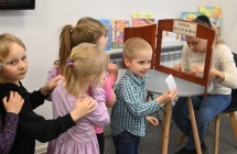 Kobieta wydająca bilety teatralne dla grupy przedszkolaków 