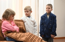 Dziewczynka i dwoje chłopców na scenie w trakcie przedstawienia teatralnego 