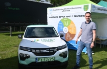 Uśmiechnięty mężczyzna stojący obok ekologicznego auta