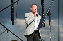 Mężczyzna stojący na scenie i mówiący do mikrofonu 