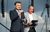 Dwoje elegancko ubranych mężczyzn na scenie - jeden mówi do mikrofonu 