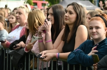 Kilka uśmiechniętych młodych kobiet stojących przed tłumem ludzi