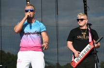 Dwoje mężczyzn na scenie. Jeden śpiewa do mikrofonu, drugi gra na keyboardzie 