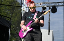 Mężczyzna z dredami na środku głowy grający na gitarze 