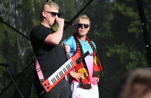 Dwoje mężczyzn na scenie. Jeden gra na gitarze, drugi śpiewa do mikrofonu