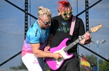 Dwoje mężczyzn na scenie. Jeden trzyma gitarę a drugi na niej gra 