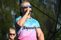 Wokalista w okularach przeciwsłonecznych śpiewający do mikrofonu na scenie 