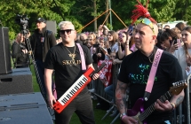 Dwoje muzyków grających przy barierkach za którymi stoją fani