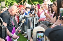 Dwoje muzyków grających przy barierkach za którymi stoją fani