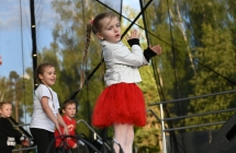 Dziewczynka wraz z rówieśnikami tańczą na scenie 