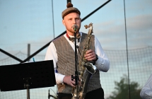 Mężczyzna trzymający saksofon. Śpiewa do mikrofonu 