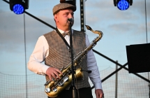 Mężczyzna śpiewajacy do mikrofonu - trzyma również saksofon 