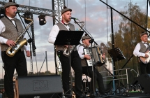 Kapela podwórkowa śpiewająca i grająca na scenie - pięcioro mężczyzn w ludowych strojach 