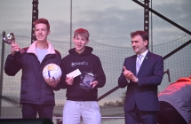 Troje mężczyzn na scenie. Jeden trzyma piłkę 