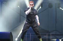 Mężczyzna otoczony spektaklem świateł podczas śpiewania do mikrofonu na scenie 