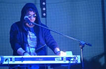 mężczyzna w kapturze oraz okularach przeciwłonecznych grający na keyboardzie 