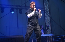 Mężczyzna w okularach przeciwsłonecznych śpiewający na scenie 