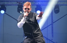 Mężczyzna śpiewający na scenie do mikrofonu 