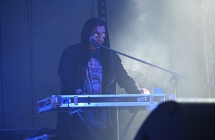 Mężczyzna grający na klawiszach. Na głowie kaptur 