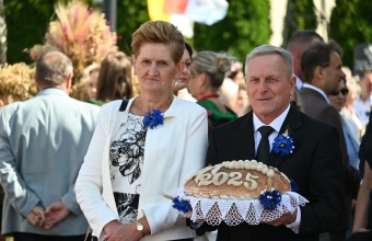 Starostowie dożynek - mężczyzna i kobieta. Kobieta trzyma bochen chleba 