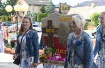 Delegacja dożynkowa wchodząca do kościoła. Dwie kobiety trzymają w rękach wieniec 