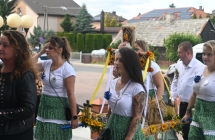 Kilka kobiet niosących wieniec dożynkowy 