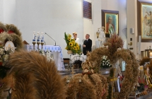 Starostowie dożynek w kościele, przed ołtarzem wieńce 