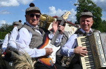 Kapela grająca na instrumentach. Siedzą na wozie konnym 