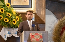 Mężczyzna w garniturze mówiący do mikrofonu w kościele 