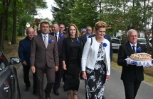 Mężczyzna niosący chleb dożynkowy. Za nim tłum ludzi