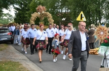 Przemarsz dożynkowy. Kilkadziesiąt osób, niektórzy niosą wieńce dożynkowe 