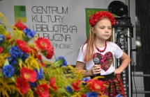 Dziewczynka w folklorystycznym stroju śpiewa piosenkę na scenie 