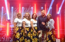 Pięć kobiet w jednakowych strojach stojących na scenie 
