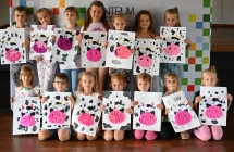 Kilkanaścioro uśmiechniętych chłopczyków i dziewczynek prezentujących prace plastyczne 
