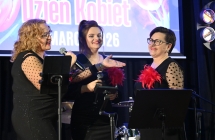 Trzy podobnie ubrane kobiety śpiewają do mikrofonu