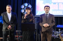 Dwóch mężczyzn i kobieta na scenie. Kobieta mówi do mikrofonu