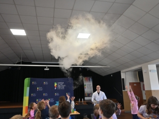 Mężczyzna w fartuchu prezentujący doświadczenia fizyczne z ciekłym azotem 