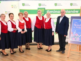 Sześć kobiet i mężczyzna - zespół ludowy. Kobiety ubrane w jednakowe stroje. 